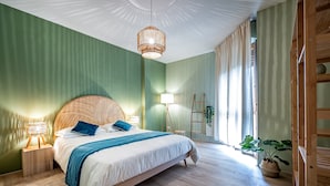 A bedroom with a large bed, bedside lamps, a wooden headboard, and a hanging light fixture.