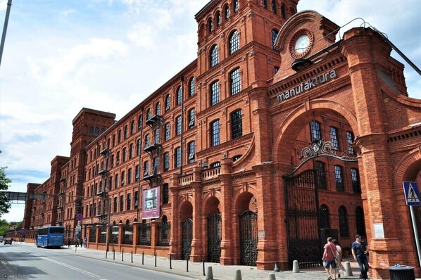 A large brick building with arched windows and a clock tower, likely a historical or industrial site.