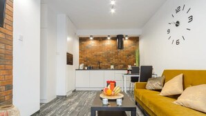 A modern living room with a yellow sofa, a coffee table, and a kitchen in the background.
