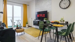 A modern living room with a TV, dining area, and a large window with curtains. - Lumina apart near Cinema Museum (Lódz)