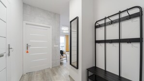 A hallway with a white door, a mirror, and a black bench with hooks. - Lumina apart near Cinema Museum (Lódz)