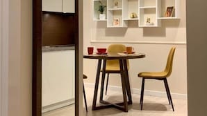 Een moderne eetruimte met een houten eettafel, twee stoelen en een hanglamp.
