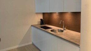 Een moderne keuken met een inbouwfornuis, spoelbak en waterkoker.