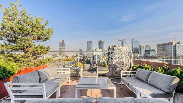 A rooftop terrace with outdoor seating, a large decorative globe, and a city skyline view. - Lumina cozy apartment with gym in the City Center (Warszawa)