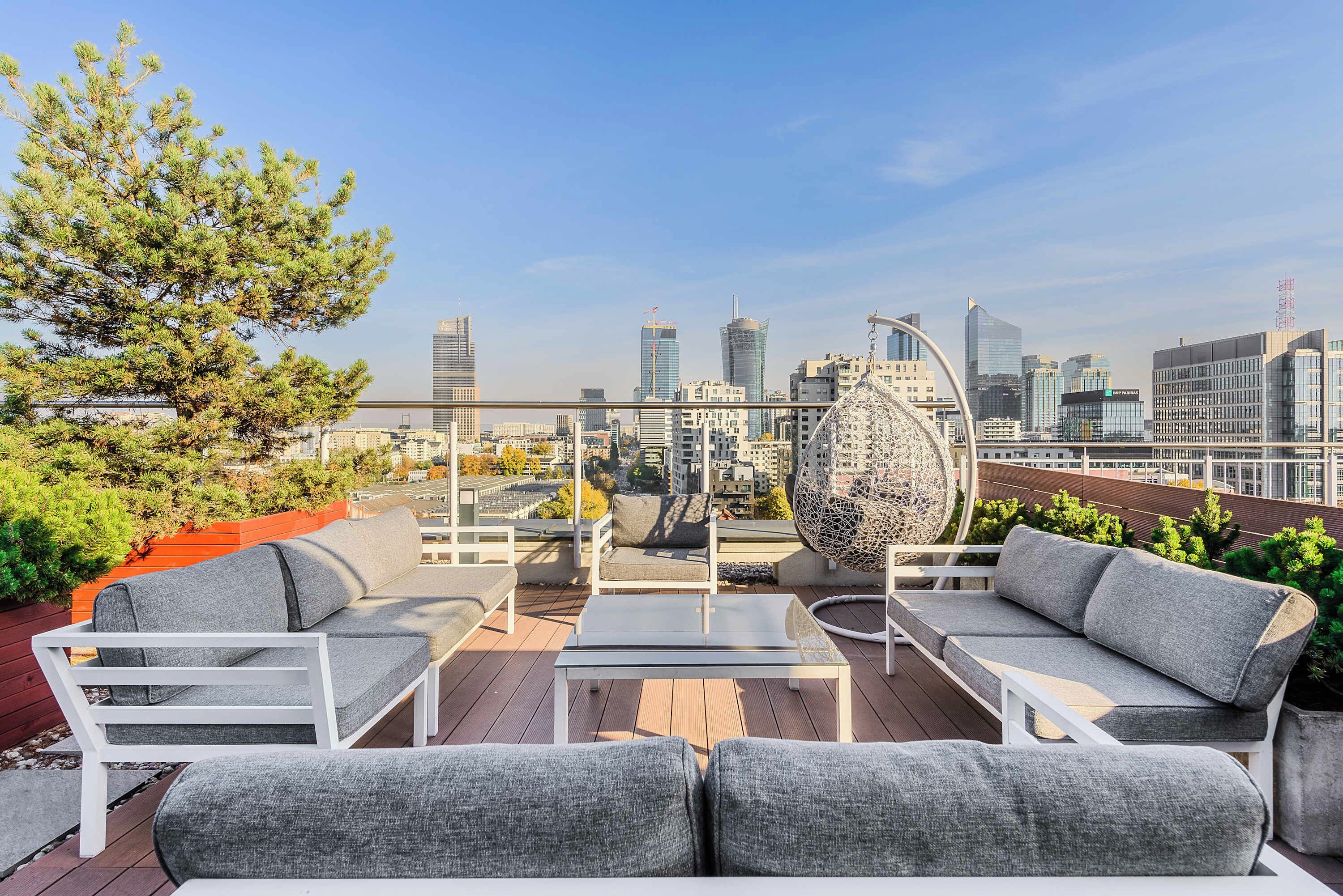 A rooftop terrace with outdoor seating, a large decorative globe, and a city skyline view.