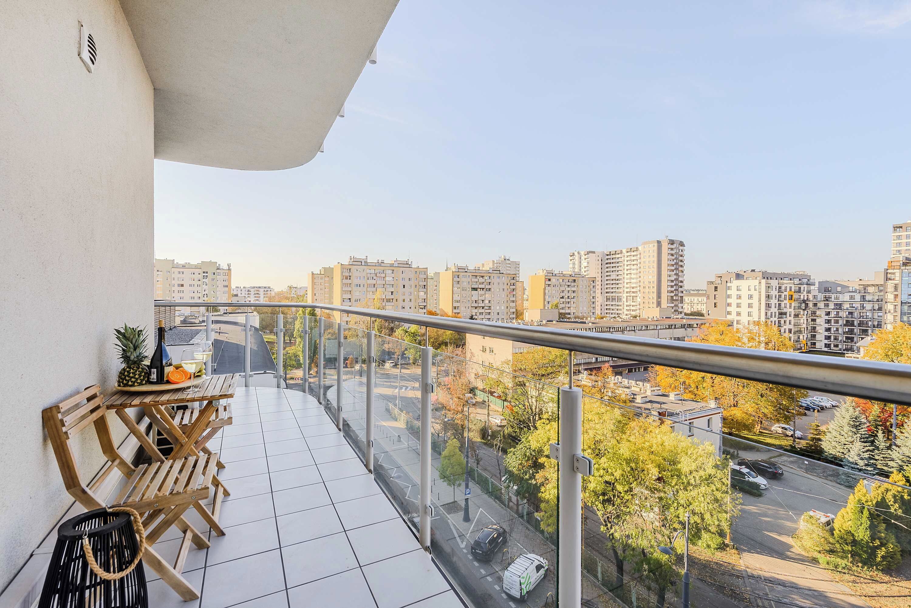 A balcony with a wooden table and chairs, a bottle, and a pineapple.