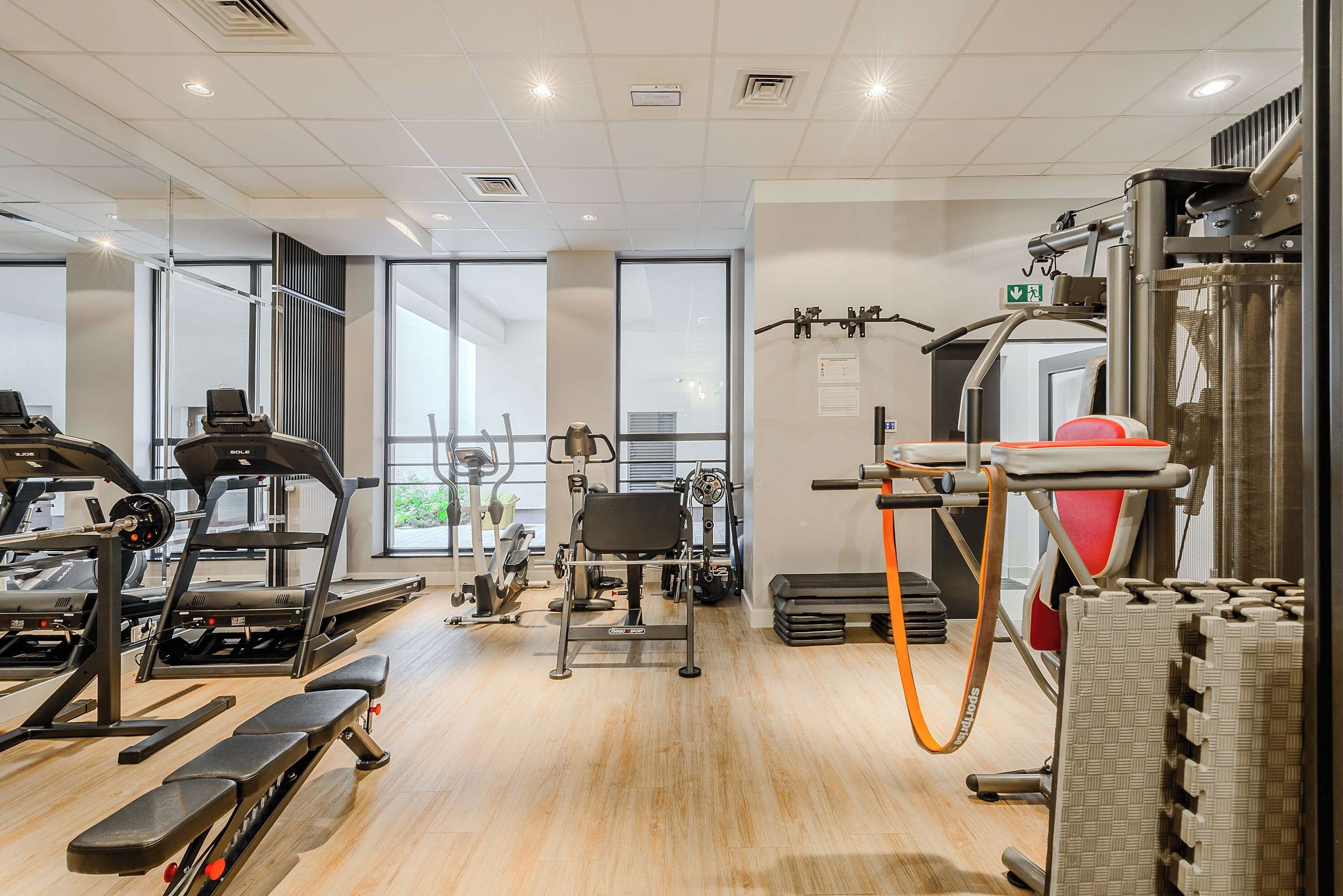 A gym with treadmills, weight machines, and a pull-up bar.