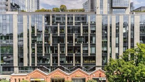 A modern building with a glass facade, multiple floors, and a brick base. - Lumina lux apartment in Warsaw (Warszawa BIG)