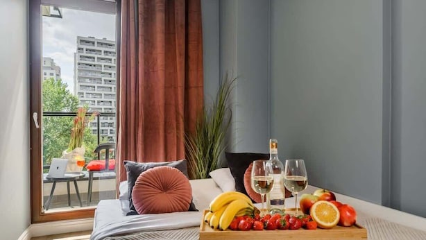 A modern bedroom with a balcony, a dining table with fruit and wine, and a laptop on the balcony. - Lumina lux apartment in Warsaw (Warszawa BIG)