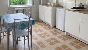 A kitchen with a dining table, chairs, white cabinets, a window with a view of greenery, and a radiator. - Apartment in Alba with free parking. Sleeps 7. Self check-in (Alba)