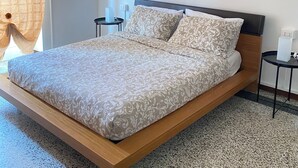 A modern bedroom with a wooden bed frame, a patterned bedspread, and a nightstand with a lamp. - Apartment in Alba with free parking. Sleeps 7. Self check-in (Alba)