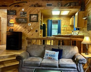 Een gezellig interieur van een chalet met een bank, een eettafel en een keukenhoek.