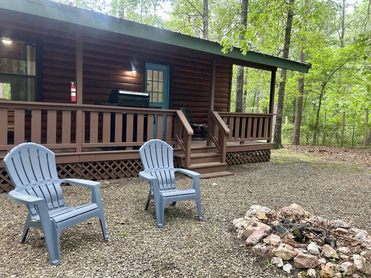Una cabaña con un porche, dos sillas Adirondack y un brasero.