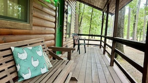 Una baita di legno con veranda, una panchina e una porta verde.