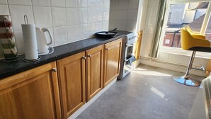 A kitchen with wooden cabinets, a black countertop, a kettle, and a coffee maker. - Ashford Cozy Apartment in Town Centre (Ashford)