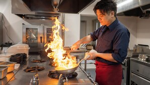 A chef cooking with flames on a stove in a professional kitchen. - Satonuma Resort Hotel Komorinu (Tatebayashi)