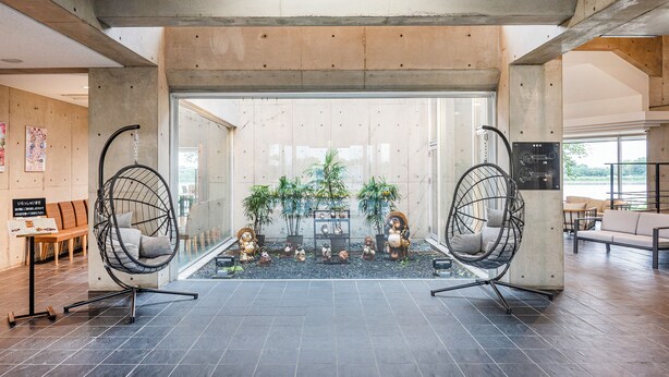 A spacious lobby with two hanging chairs, a reception desk, and a seating area with a view of the outdoors. - Satonuma Resort Hotel Komorinu (Tatebayashi)