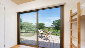 A room with a large sliding glass door leading to an outdoor deck with a table and chairs. - Satonuma Resort Hotel Komorinu (Tatebayashi)