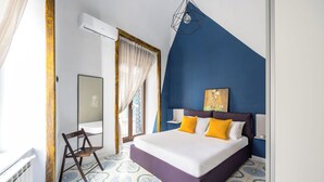 Une chambre à coucher avec un lit, une chaise, une fenêtre avec des rideaux et un mur d’accent bleu.