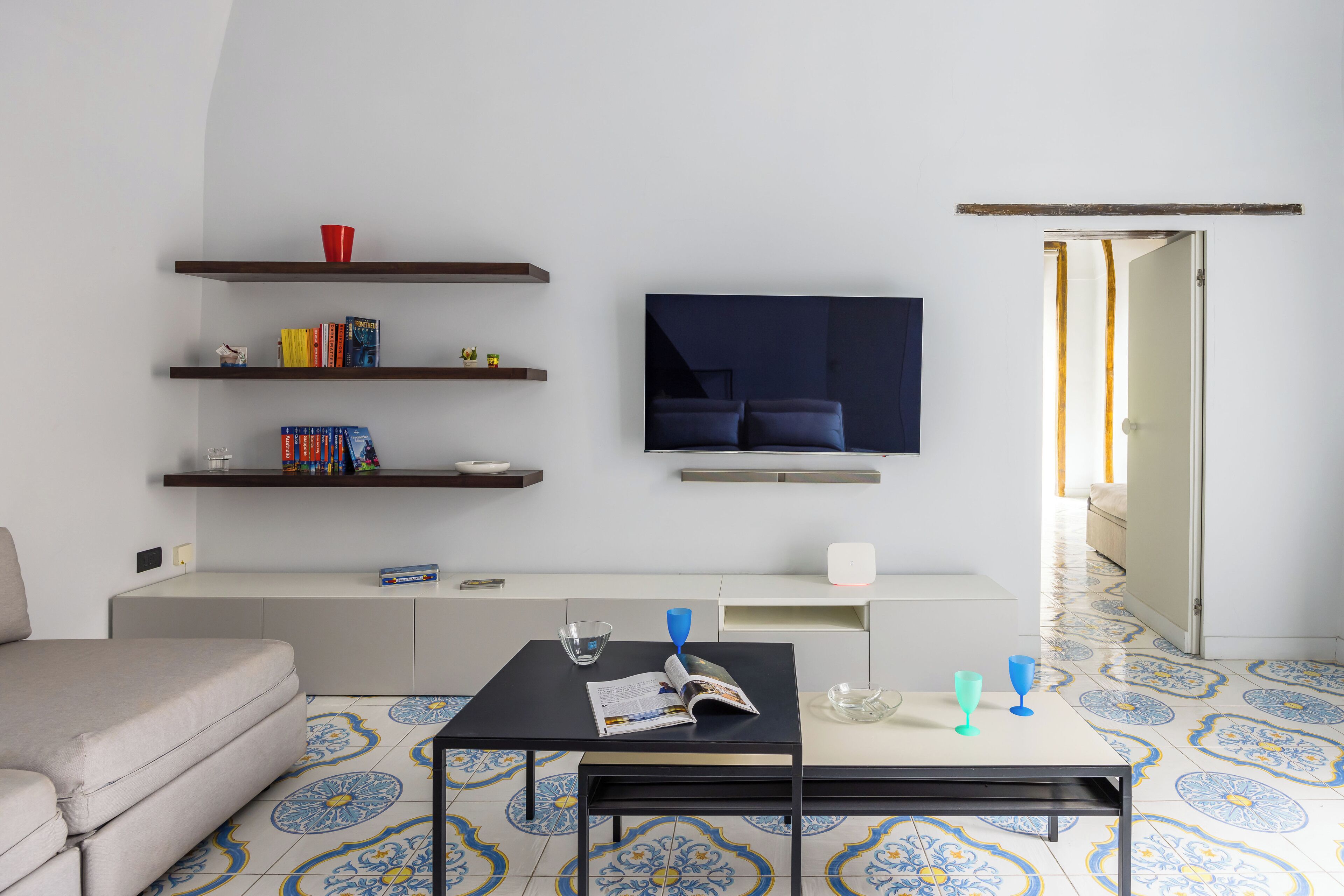 Un salon moderne comprenant un canapé, une table basse, un téléviseur et des étagères remplies de livres et d’objets décoratifs.