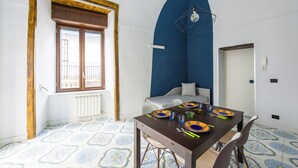 Un coin repas avec une table dressée pour deux personnes, une fenêtre offrant une belle vue et un mur d’accent bleu.