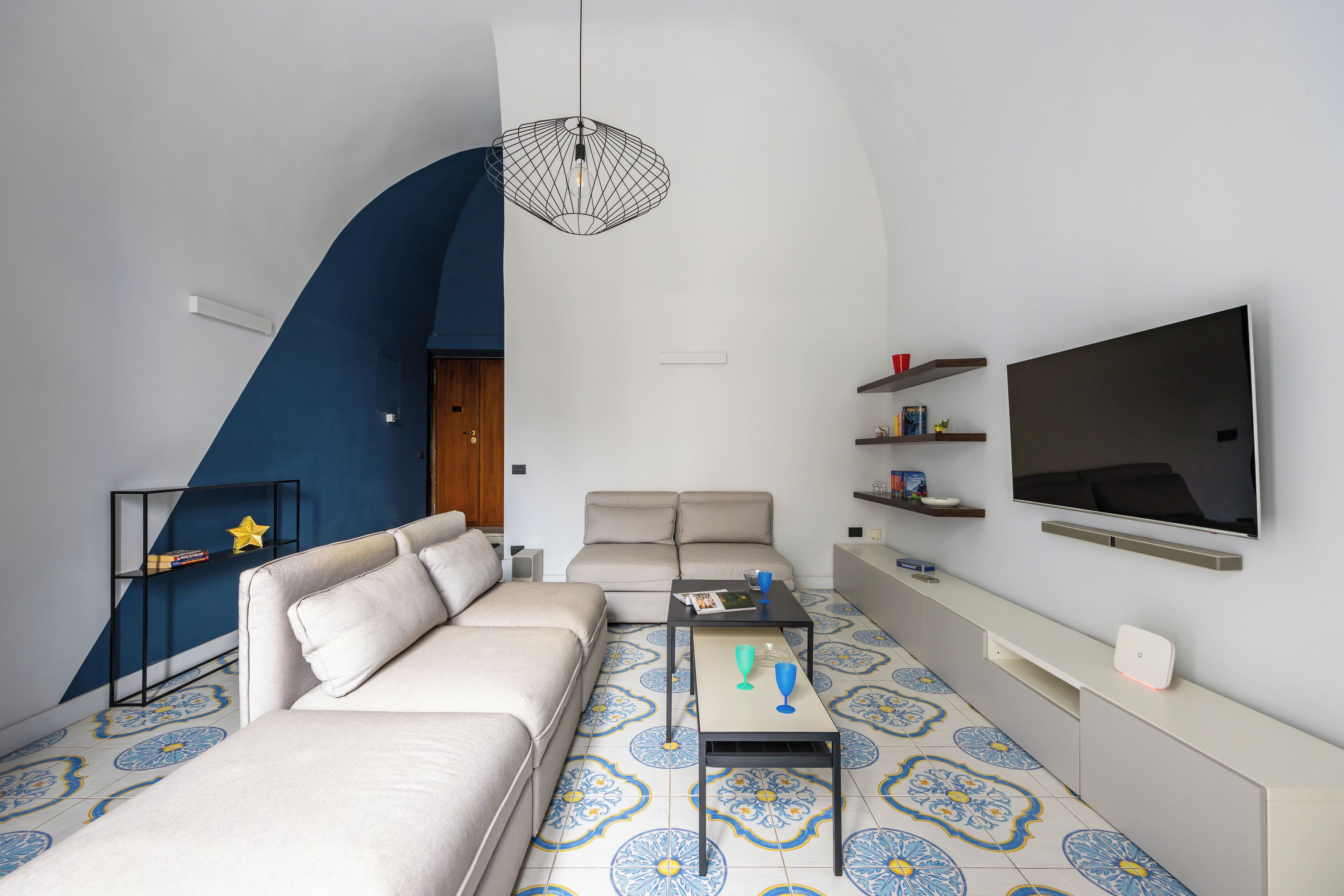 A modern living room with a sofa, coffee table, TV, and patterned floor tiles.