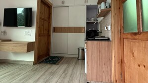 A compact kitchen with white cabinets, a wooden countertop, and a built-in microwave. - Rasberry Homes (Dhari)