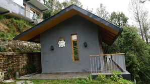 A modern house with a grey exterior, a wooden sloped roof, and a balcony with a railing. - Rasberry Homes (Dhari)