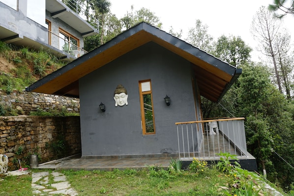 Ein modernes Haus mit grauer Fassade, einem geneigten Holzdach und einem Balkon mit Geländer.