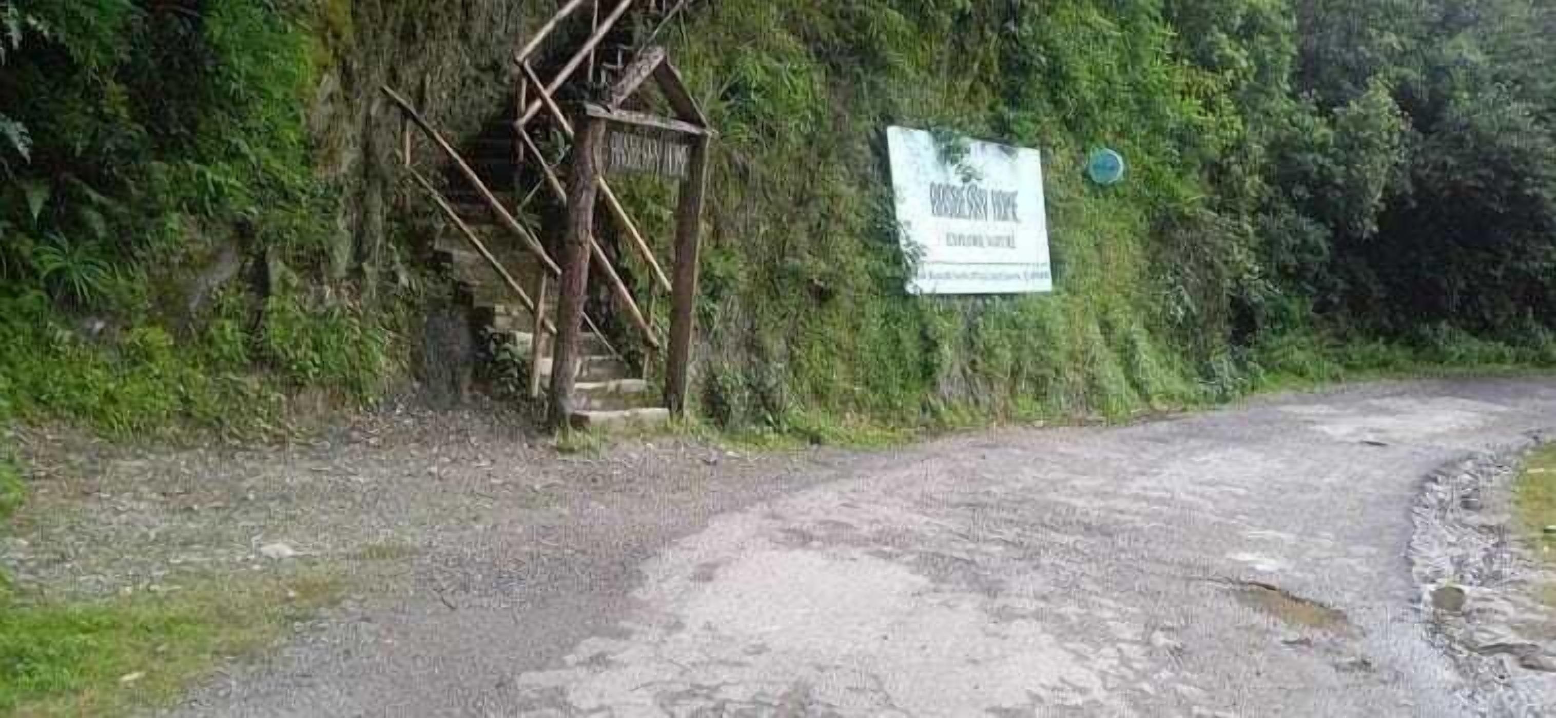 Ein Schild an einer Wand, eine Holztreppe und ein Kiesweg.