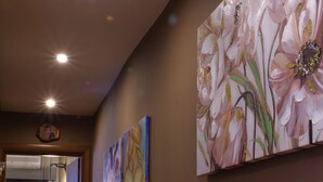 A hallway with a painting of flowers on the wall, a chair, and a small table. - Violeta s Seaview Apartment in Piraeus (Piraeus)