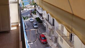 A balcony with a view of a street, cars, and a building with balconies. - Violeta s Seaview Apartment in Piraeus (Piraeus)