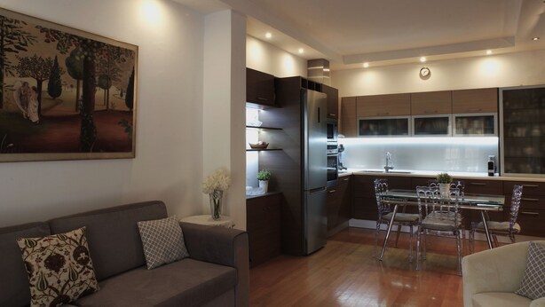 A modern kitchen with a refrigerator, stove, and dining area. - Violeta s Seaview Apartment in Piraeus (Piraeus)