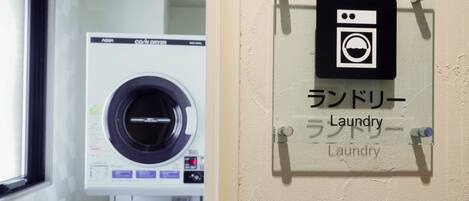 A laundry room with a front-loading washing machine and a wall-mounted sign indicating the location.