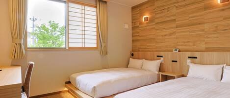 A hotel room with two beds, a desk, and a view of the outdoors.