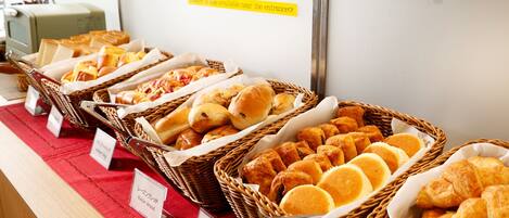 A buffet with various baked goods including bread, pastries, and rolls.
