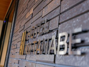 Uma parede com o texto "HOTEL MIKITA NABA" em letras metálicas.