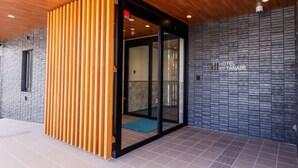 A modern hotel entrance with a wooden slatted door, a glass door leading inside, and a sign reading "HOTEL KITA NABE". - Hotel Kii Tanabe (Tanabe)