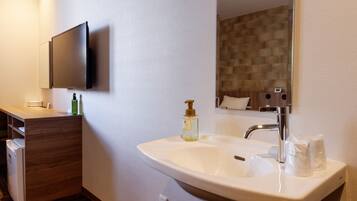 Un baño moderno con un lavamanos grande, un espejo, un televisor montado en la pared y un mueble de tocador de madera.