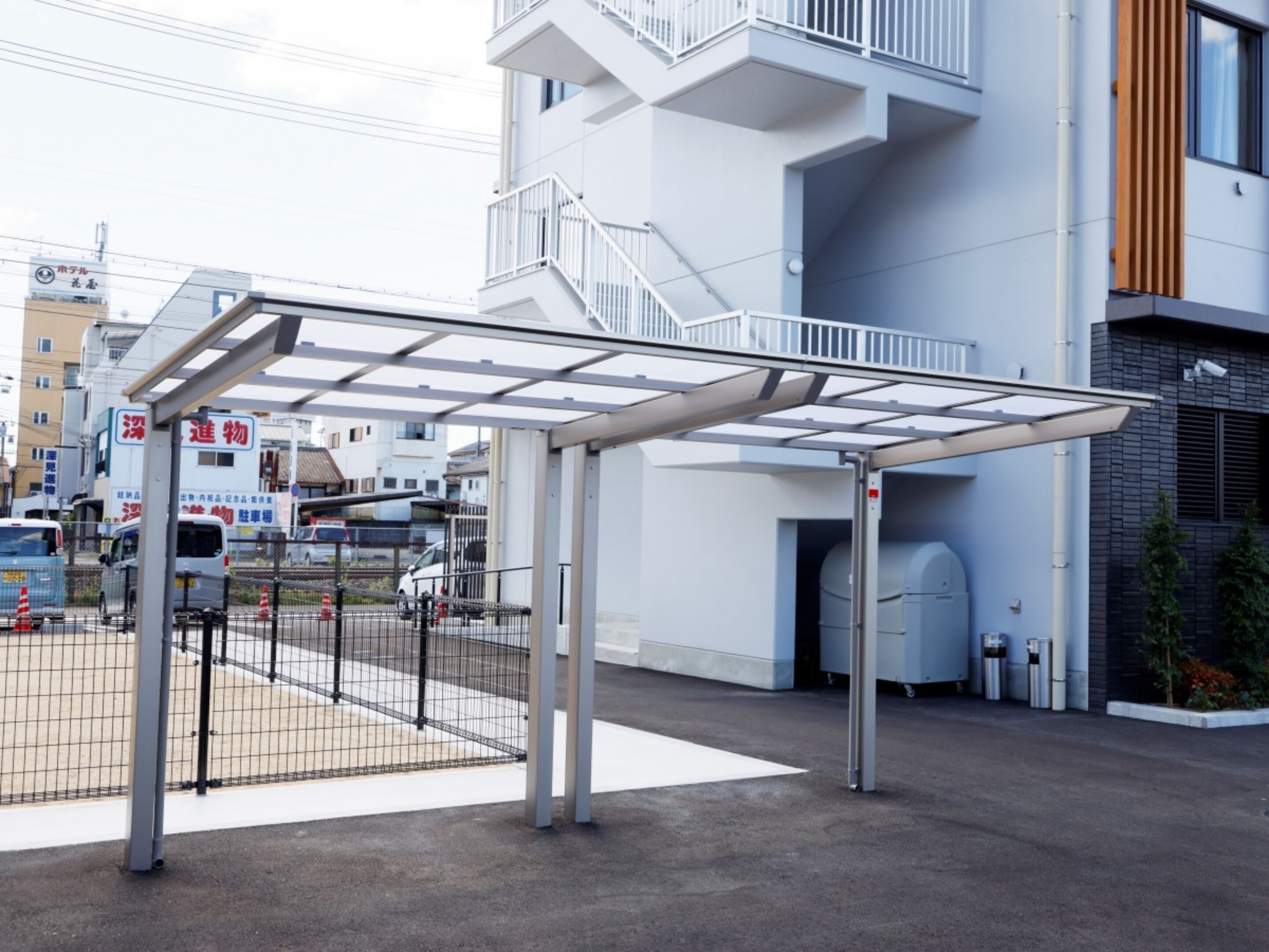 Un edificio moderno con una zona de acceso cubierta, una escalera y una sección de estacionamiento protegida.