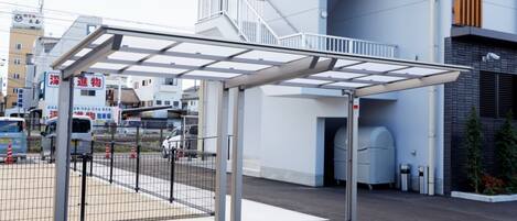 Un edificio moderno con una zona de acceso cubierta, una escalera y una sección de estacionamiento protegida.