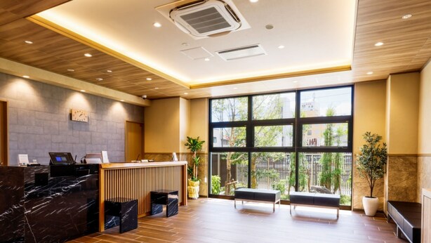 A reception area with a marble counter, wooden flooring, and large windows offering a view of the outdoors. - Hotel Kii Tanabe (Tanabe)