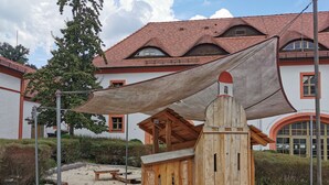 A wooden playhouse with a slanted roof and a large canopy. - Gästehäuser St Marienthal (Ostritz)