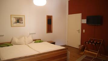 Um quarto com uma cama de madeira, uma televisão fixada na parede e uma porta.
