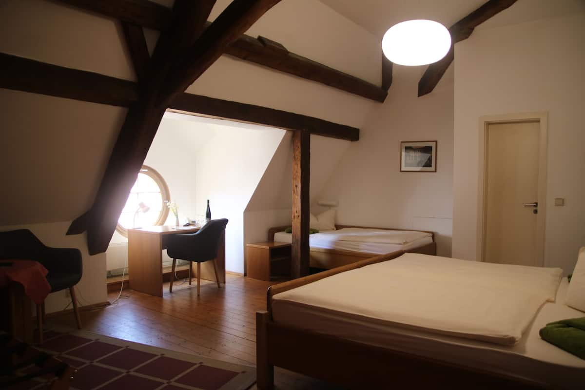 Un dormitorio con techo de madera, cama, escritorio y silla.