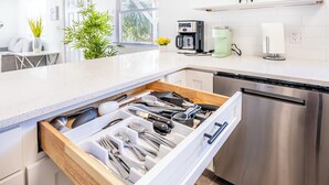 Une cuisine moderne équipée d’un lave-vaisselle en acier inoxydable, d’une machine à café et d’un distributeur d’eau sur le plan de travail.