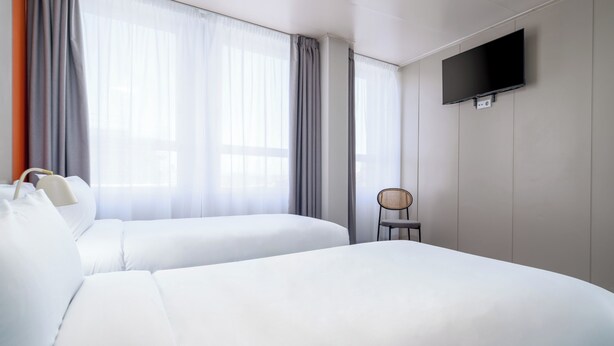 A hotel room with two beds, a flat-screen TV mounted on the wall, and a chair. - STAYSOME Porto Herculano (Porto)