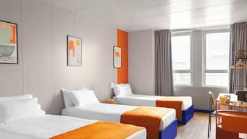A hotel room with three beds, a desk, and a chair.