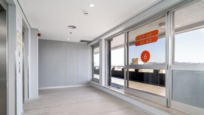 A modern hotel room with a large window, a wooden floor, and a view of the cityscape. - STAYSOME Porto Herculano (Porto)
