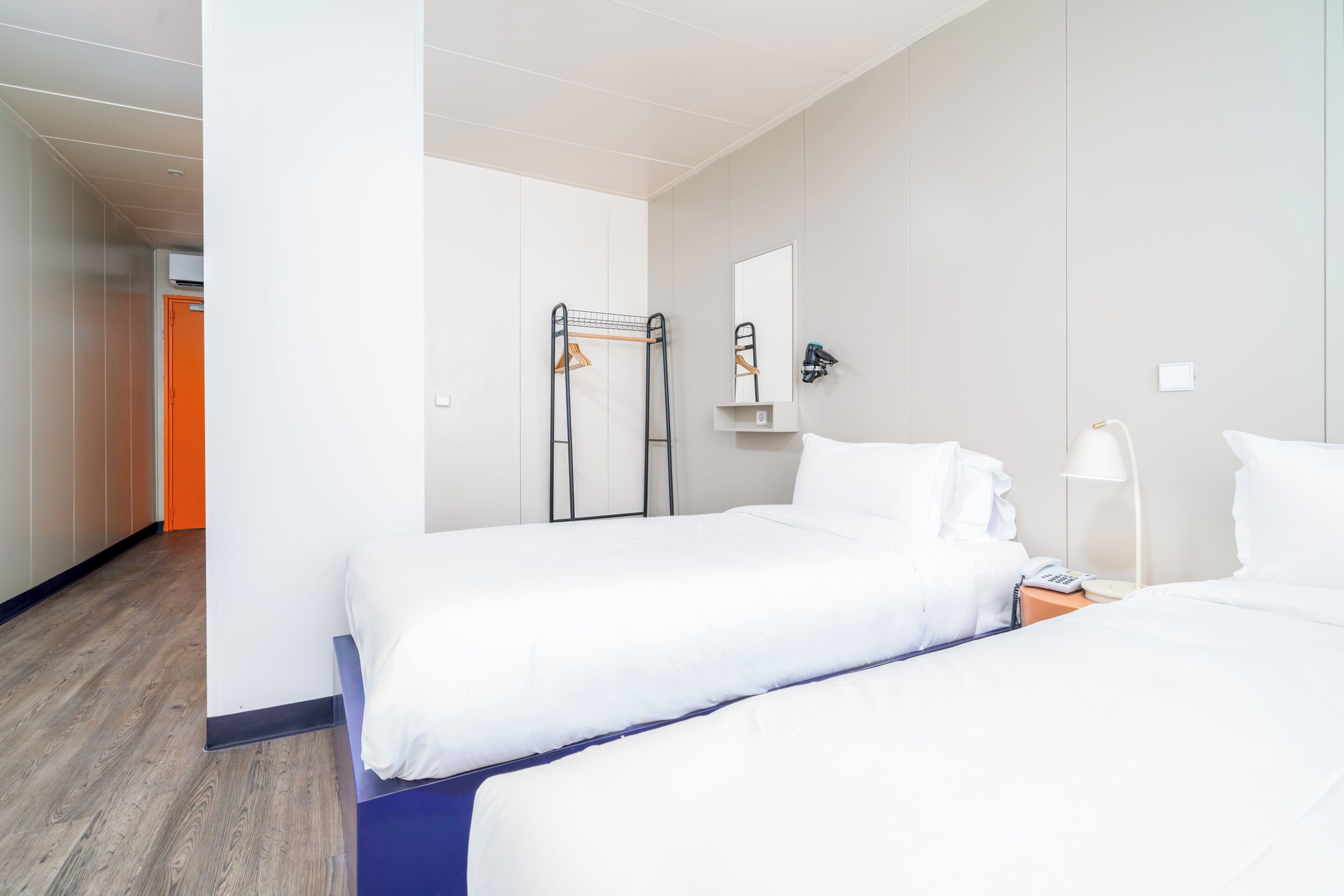 Habitación de hotel con dos camas, un armario, un espejo y una percha.